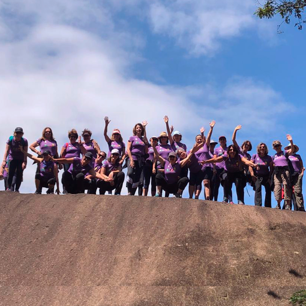 Grupo de alunas do Projeto Mulher no topo de montanha com braços levantados
