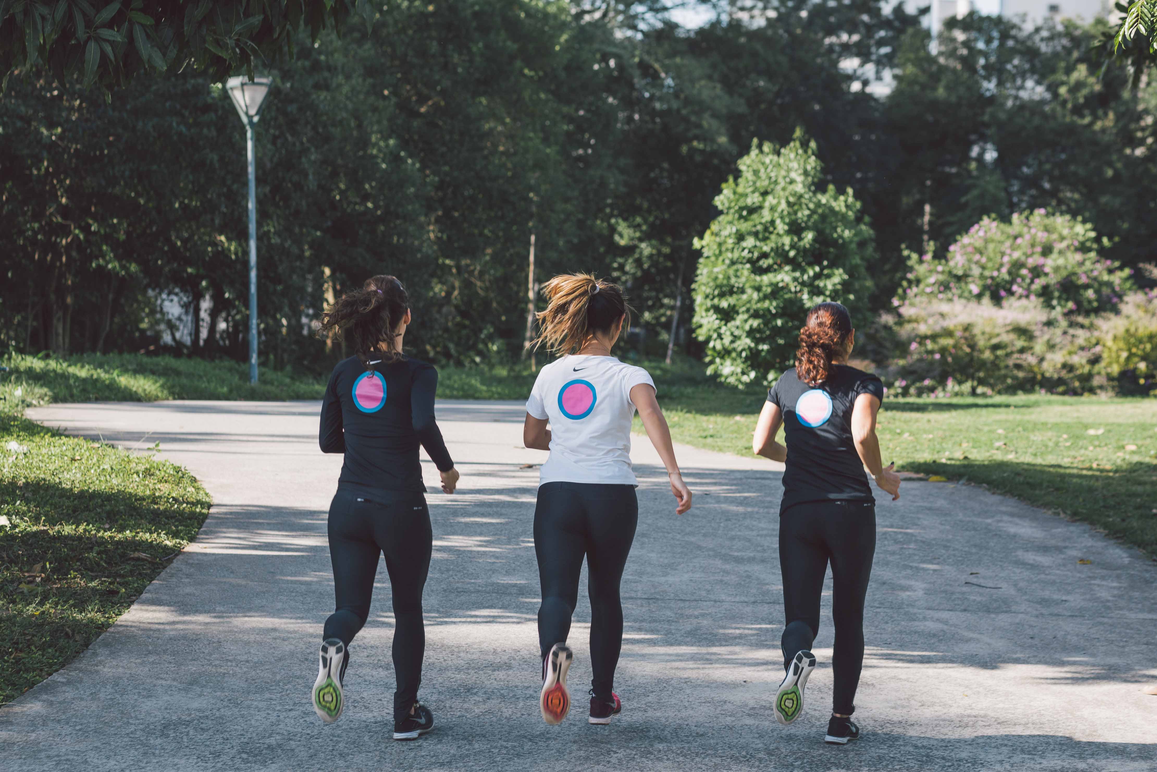 Mulheres correndo juntas no parque com camiseta do Projeto Mulher